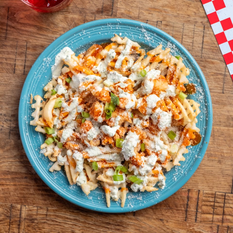 Waffle fries topped with buffalo chicken, blue cheese crumbles, ranch dressing, and green onions.